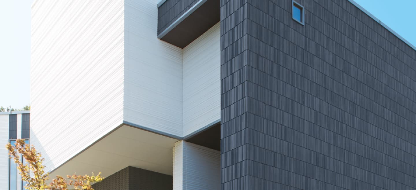 Здание, облицованное оригинальными фасадными панелями из Японии от компании NICHIHA, известной своими технологичными решениями. Панели обладают наногидрофильным покрытием и функцией самоочистки, что обеспечивает долговечность и эстетичность фасада. Технология бесшовного монтажа придаёт зданию современный вид.